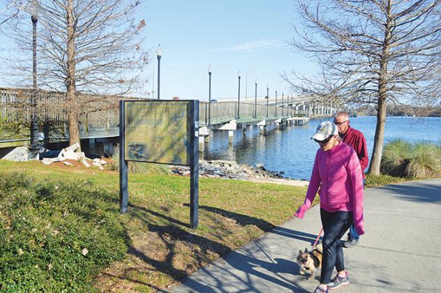 A couple walks their dog at the Palatka riverfront Friday next to the closed boardwalk that will soon be repaired and reopened.