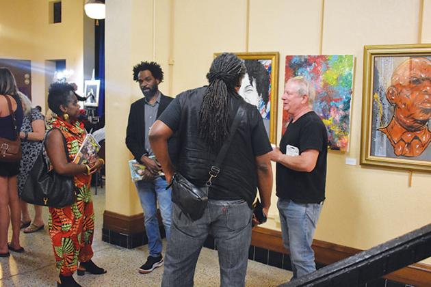Artist Overstreet Ducasse, second from left, who drew the paintings in that room of the Larimer Arts Center in Palatka, talks to people at the art show “Metamorphosis II: The Evolution of the Black Artist” on Friday.