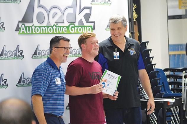 Craig Alexander, left, fixed operations director for Beck Automotive Group, and PHS automotive program instructor David Garrison, right, present a certificate to one of the program’s students.