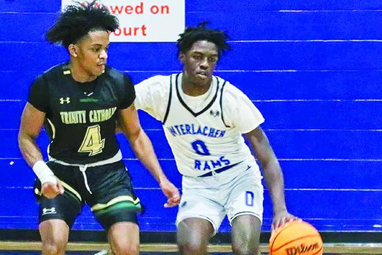 Interlachen’s Chris Johnson (right) controls the basketball as Ocala Trinity Catholic’s Torie Fairley tries to get to it during Tuesday night’s district tournament game. (RITA FULLERTON / Special to the Daily News)
