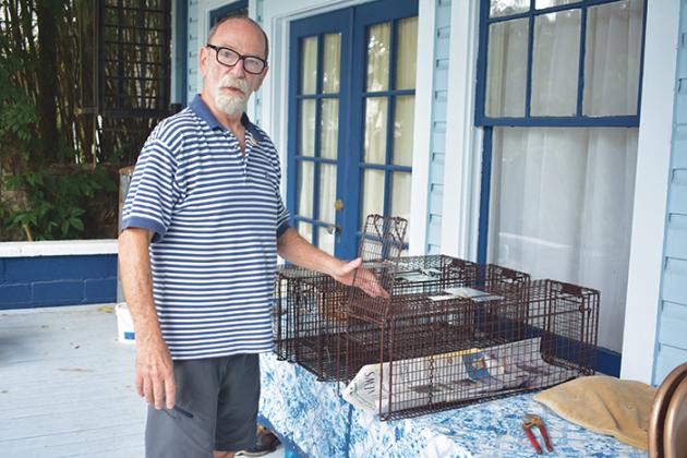 Wes Tuten stands on his front porch to show off one of the traps he uses to catch stray cats that are later spayed or neutered.