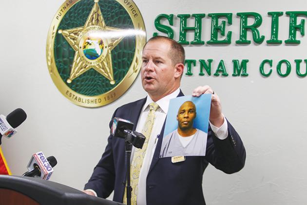 Sheriff Gator DeLoach holds a picture of Lorenzo Hudson, the suspect of a 2015 cold case murder, during a press conference Tuesday in Palatka.