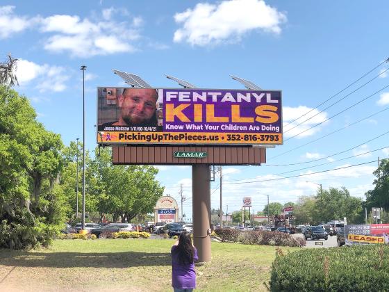 Photo courtesy of Sherry Mills -- Sherry Mills takes a photo of the digital billboard sign in Ocala that she and her husband, Rick, helped pay for along with 50 other families who lost loved ones to fentanyl overdoses. 