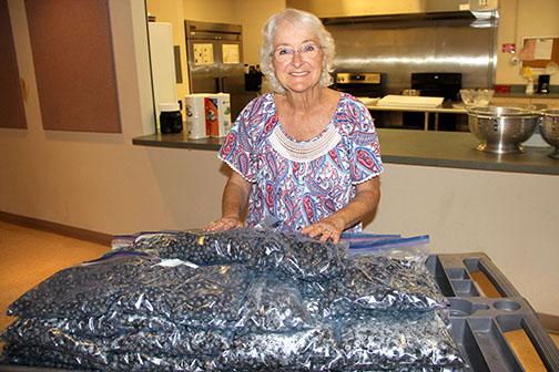 Linda Bazar, a longtime volunteer with the Bostwick Blueberry Festival, shows a cart she and other volunteers packed with bags of blueberries Monday. -- TRISHA MURPHY/Palatka Daily News 