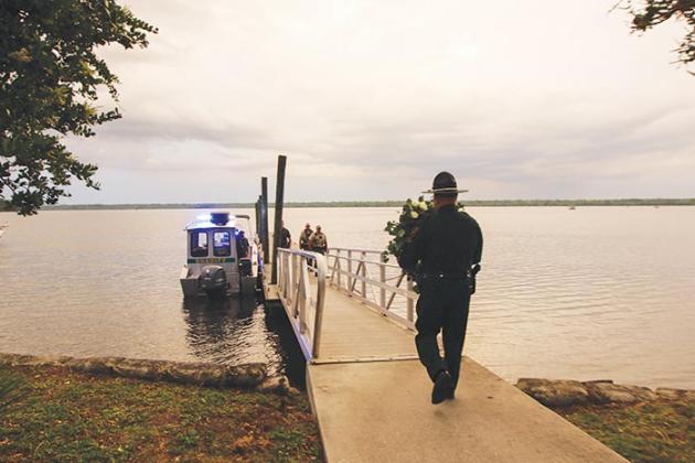 A member of the Putnam County Sheriff’s Office Honor Guard delivers a wreath honoring fallen Florida law enforcement officers to be placed in the St. Johns River.