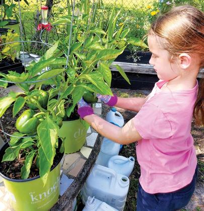 Annabelle Price, seen here in her garden, learned that gardening is a lot of work, with watering and checking for weeds, among other duties.