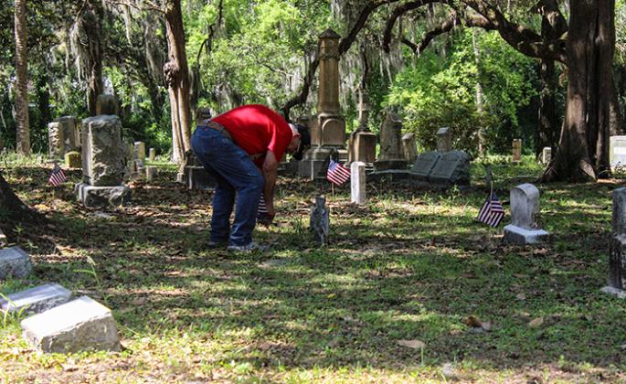 A man places U.S. flags on gravesites ahead of Memorial Day in 2021.