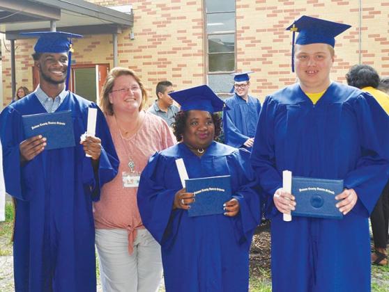 Mellon Learning Center graduates take pictures with one of the school’s employees after the commencement ceremony Monday afternoon.