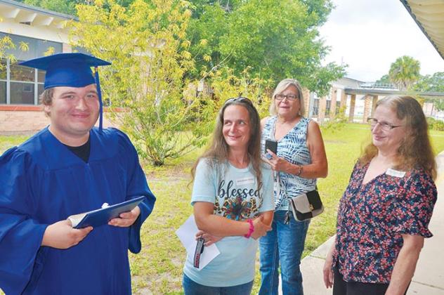 A Mellon Learning Center graduate holds his diploma while his loved ones look on.