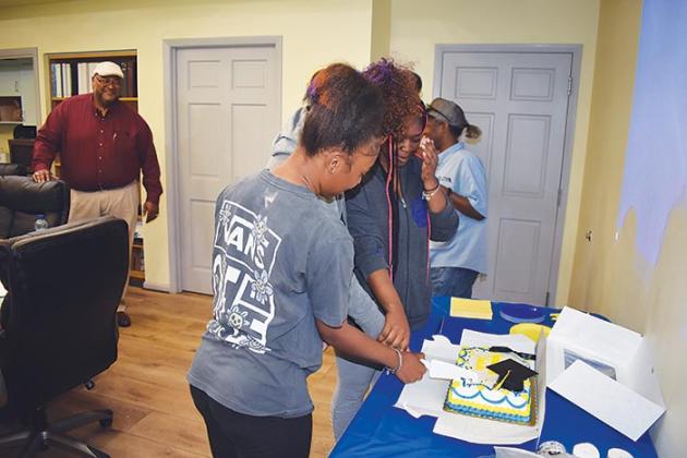 Sa’Miya Edward, Raven Bramlitt and Lamiya Lawson cut the cake Wednesday during a graduation celebration at the Palatka Housing Authority headquarters.