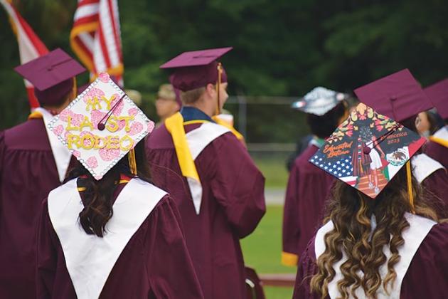 Two Crescent City Junior-Senior High School graduates wear decorated mortarboards during the school's commencement ceremony Thursday evening.