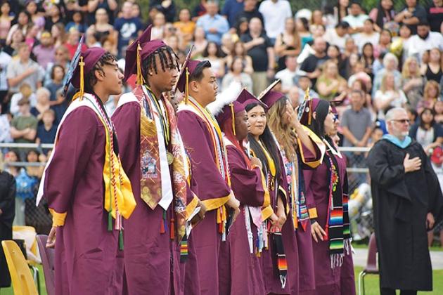 Crescent City Junior-Senior High School graduates stand while the national anthem plays during the school's commencement ceremony Thursday evening.