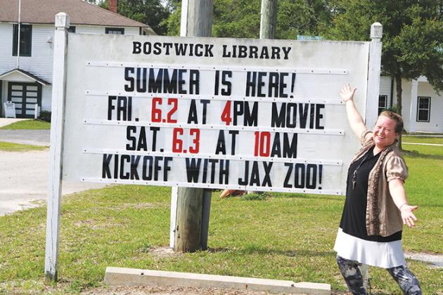 TRISHA MURPHY/Palatka Daily News  McCuiston-Boerman stands in front of the Bostwick Library sign that announces summer is here.
