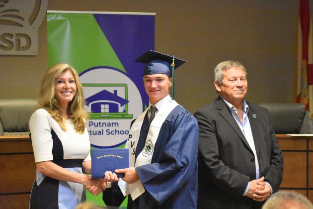 Tyler Daughtery, center, receives his Putnam Virtual School diploma from Principal Mary Wood while Superintendent Rick Surrency stands with them.