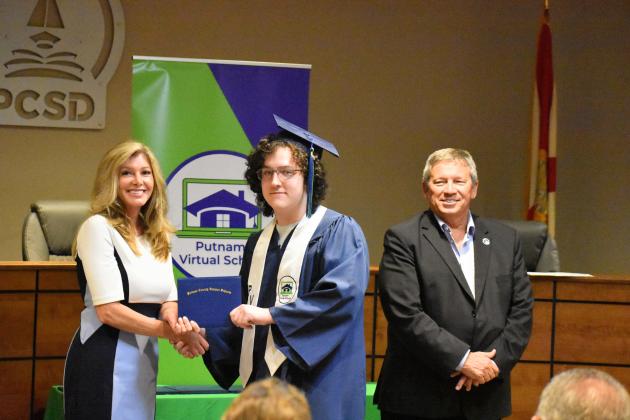 Coby Fletcher, center, receives his Putnam Virtual School diploma from Principal Mary Wood while Superintendent Rick Surrency stands with them.