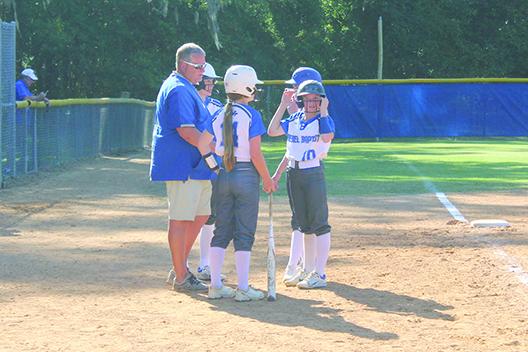 Peniel Baptist Academy softball coach Jeff Hutchins (left) talks to some of his players during a timeout in the District 4-2A championship last week against Daytona Beach Father Lopez. (MARK BLUMENTHAL / Palatka Daily News)