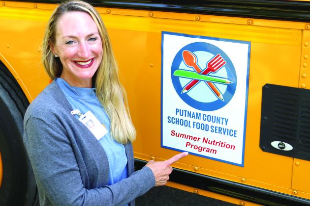Nikki Hawthorne, Putnam County School Food Service director, stands in front of the sign promoting the food service’s summer nutrition program. (TRISHA MURPHY/Palatka Daily News)