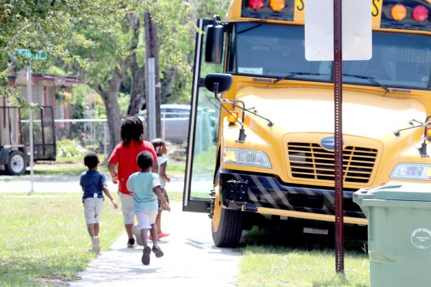 Children run toward the school bus on Washington Street in Palatka to get lunches the Putnam County Food Service is handing out to area children across Putnam County Monday through Thursday. (TRISHA MURPHY/Palatka Daily News)
