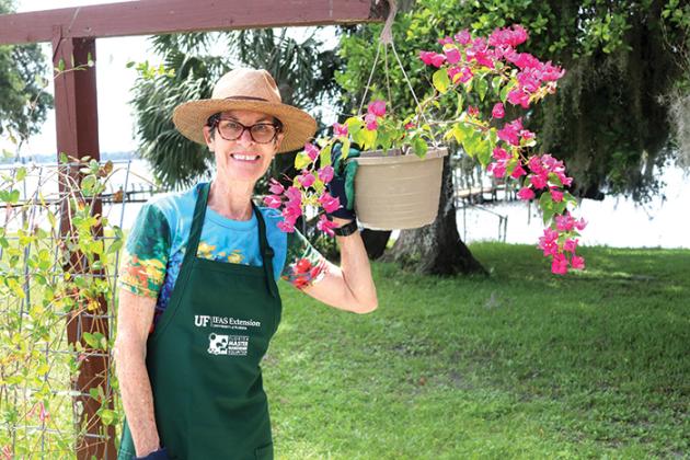 Photo by TRISHA MURPHY / Bostwick resident Hollis Bliss, a Master Gardener volunteer since October, stands next to one of the hanging potted plants she has in her home garden. 