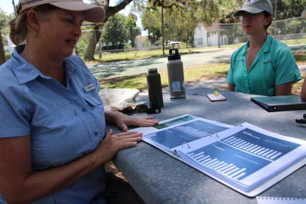 St. Johns Riverkeeper Lisa Rinaman, left, explains the varied levels of salinity and turbidity (river clarity) in the St. Johns River at Downtown Park in Welaka on Thursday. (CASMIRA HARRISON/Palatka Daily News)