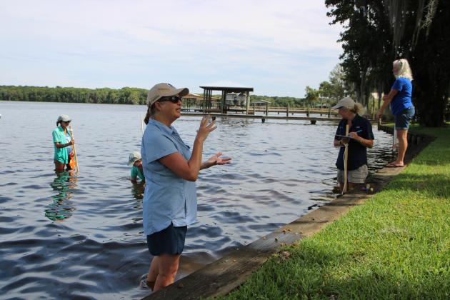 St. Johns Riverkeeper Lisa Rinaman, foreground, explains to several nearby residents what her team was doing in the river in Welaka on Thursday as resident Mary Edwards, right, waches the team gather data on river grasses in the St. Johns River. (CASMIRA HARRISON/Palatka Daily News)