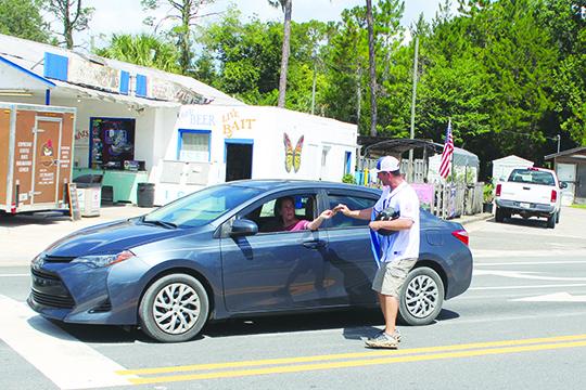 Melrose  ssistant coach Mark Musgrove gets a donation from a driver at the corner of State Roads 21 and 26 during a fundraiser Saturday. (MARK BLUMENTHAL / Palatka Daily News)