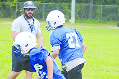 Interlachen Junior-Senior High football defensive coordinator Jordan Smalenski watches over Cecil Saunders (left) and Colten Bishop during a drill on the first day of camp last week. (MARK BLUMENTHAL / Palatka Daily News)