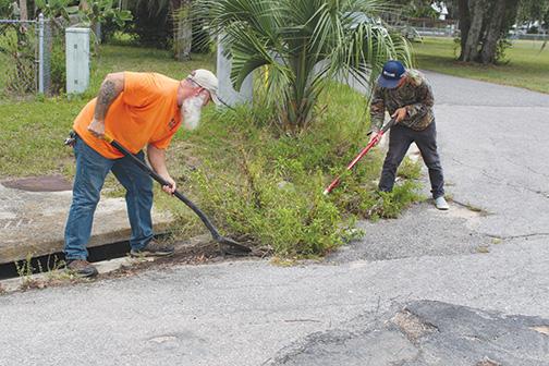 MARY KAYE WELLS/Palatka Daily News. Interlachen Public Works Department employees Shelton Griffis (left) and Mike Cemer (right) clean the town's storm drains Tuesday in preparation for Hurricane Idalia. 