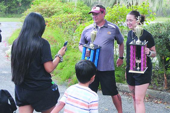 Crescent City boys cross country coach Jeff Lease (left) and girls cross country coach Alex Bittinger, Lease’s stepdaughter, pose with the All-Putnam County cross country team championship trophies on Tuesday. (MARK BLUMENTHAL / Palatka Daily News)