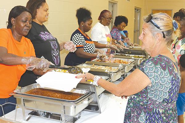 TRISHA MURPHY/Palatka Daily News – Italy Czeczeli, right, is served food by a volunteer Tuesday during a Thanksgiving meal giveaway at the Price-Martin Community Center in Palatka.