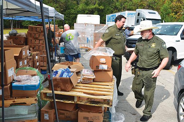 BRANDON D. OLIVER/Palatka Daily News -- Putnam County Sheriff's Office deputies distribute food to people's cars during Epic-Cure's giveaway Wednesday.