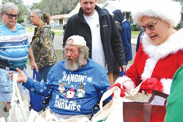 TRISHA MURPHY/Palatka Daily News – Mrs. Claus hands out gifts to Bread of Life neighbors Friday during an event to provide local residents in need with vital items during the holiday season.