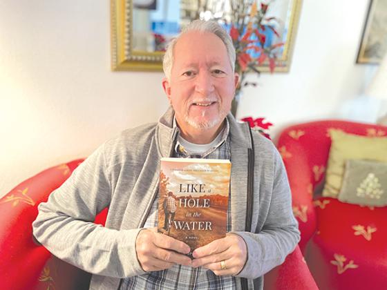 Submitted photo – John Neil Sherouse Jr. holds his book, “Like a Hole in the Water,” a historical fiction novel he wrote to honor Palatka, his hometown.