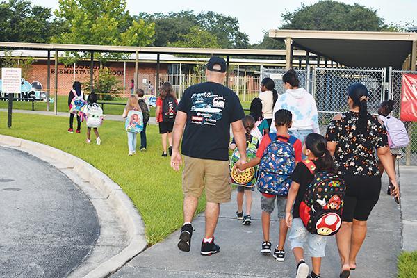File photo. Parents and children head into William D. Moseley Elementary School on the first day of school in 2023. 
