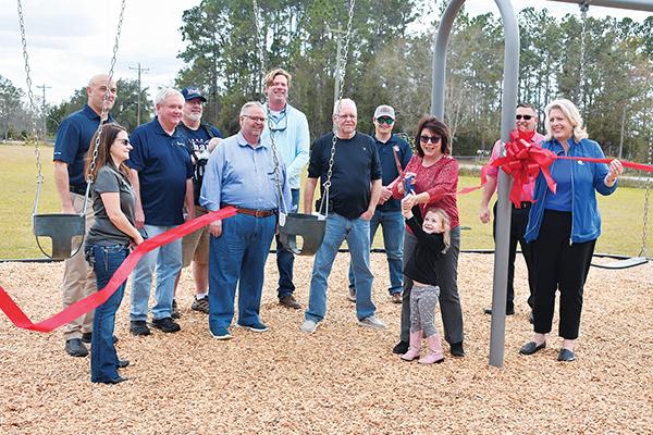 BRANDON D. OLIVER/Palatka Daily News – Lyndie Wilkinson, the 4-year-old granddaughter of County Commissioner Leota Wilkinson, gets help cutting the ribbon at the ceremonial unveiling of new equipment at Etoniah Community Park in Bardin on Friday.