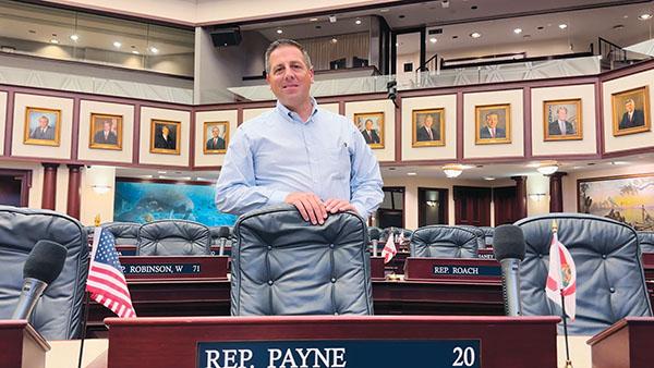 Submitted photo – Welaka Mayor Jamie Watts, who is running for a seat in the Florida House, stands behind the chair where state Rep. Bobby Payne, R-Palatka, sits in the Legislature.