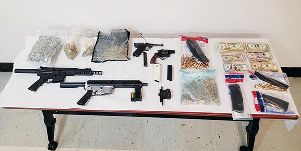Photo courtesy of the Palatka Police Department – A table full of guns, ammunition, drugs and cash are on display after Palatka Police Department officers confiscated them as evidence from an Eagle Street house.