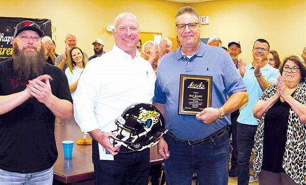 TRISHA MURPHY/Palatka Daily News – Beck Automotive Group President and CEO Breck Sloan, left, holds a Jacksonville Jaguars helmet signed by former player Fred Taylor that was presented to Hal Magee, right, Friday at Magee’s retirement celebration.