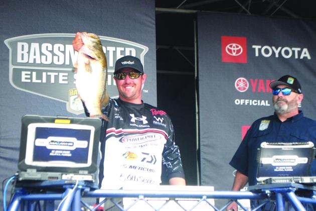 With tournament emcee Dave Mercer watching, MAXAM Tire Bassmaster Elite at the St. Johns River champion Cory Johnston shows off one of his five catches to clinch the crown on Sunday. (GREG WALKER / Daily News correspondent)