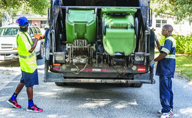 Palatka sanitation workers load trash into the truck Tuesday morning.