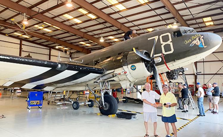 Yacht club members stand next to the plane transporting their donated canopy.