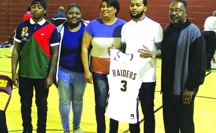 Jerrell Oxendine holds his retired No. 3 Crescent City High School boys basketball uniform while posing for pictures with, from left, his brother Jaylon, sister Tiana, mom Titiania, and father Bryant on Monday. (MARK BLUMENTHAL / Palatka Daily News)
