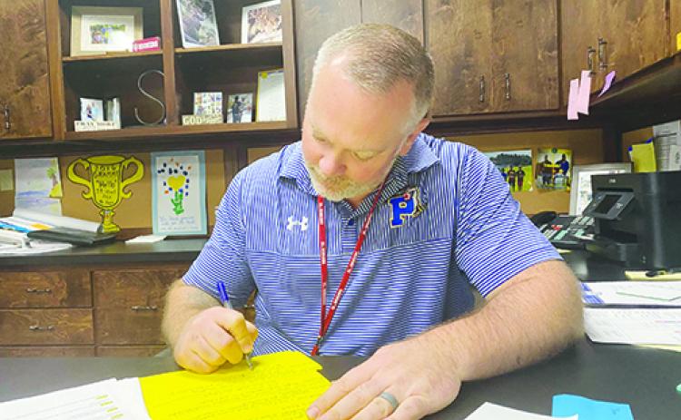 Palatka High School Principal J.T. Stout finishes paperwork Friday as the he confirmed the cancellation of several school field trips due to coronavirus.