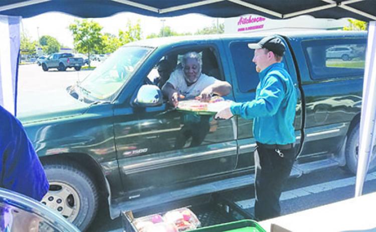 Cody Johnson distributes a meal to a local resident Saturday at Hitchcock’s Market in East Palatka during the store’s event to benefit people affected by COVID-19.