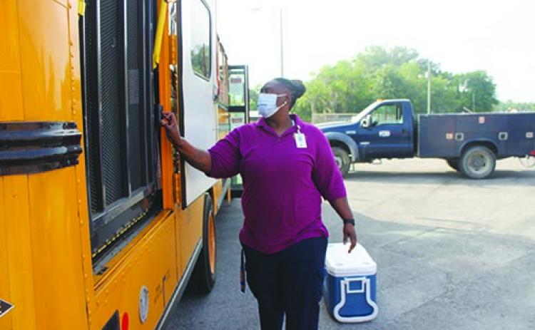 Keyonda Gilmore, Putnam County School District’s central location route coordinator, loads a bus with food Thursday to distribute to students through the district’s feeding program.