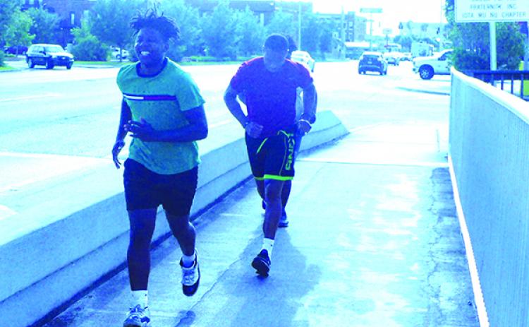 Near the foot of Memorial Bridge on the Palatka side, Palatka residents Victor Johnson, left, and Jeremiah Gilyard begin their run over the bridge late Friday afternoon. (MARK BLUMENTHAL / Palatka Daily News)