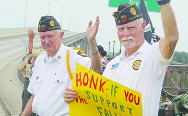American Legion Bert Hodge Post 45 members wave to cars Monday in Palatka to honor members of the military.