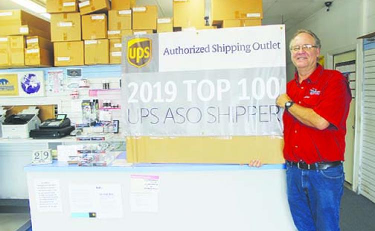 City Shippers owner Greg Bacon displays the banner he got from UPS for being one of the top 100 shipping partners in the country.