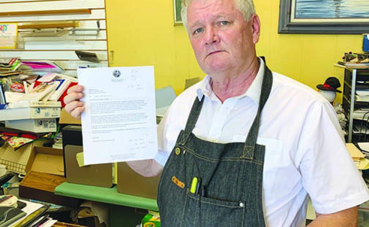 Graphics II owner Sam Deputy holds a letter he received from the state asking if his business was “owned or controlled” by the Communist Party of China.