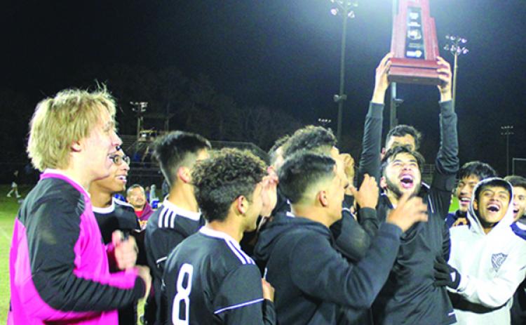 Fernando Jimenez-Cruz holds the District 4-3A championship trophy up as his Crescent City High School boys soccer teammates celebrate their title Feb. 7 in Gainesville against Keystone Heights. (MARK BLUMENTHAL / Palatka Daily News)